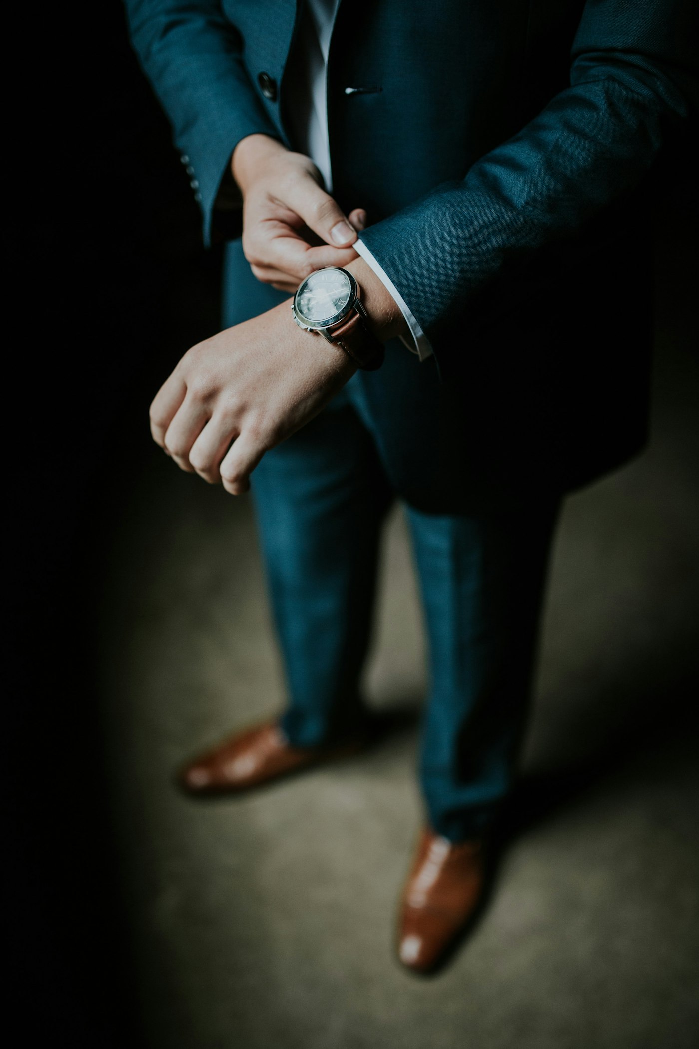 Manschette eines blauen Sakkos und braune Schuhe